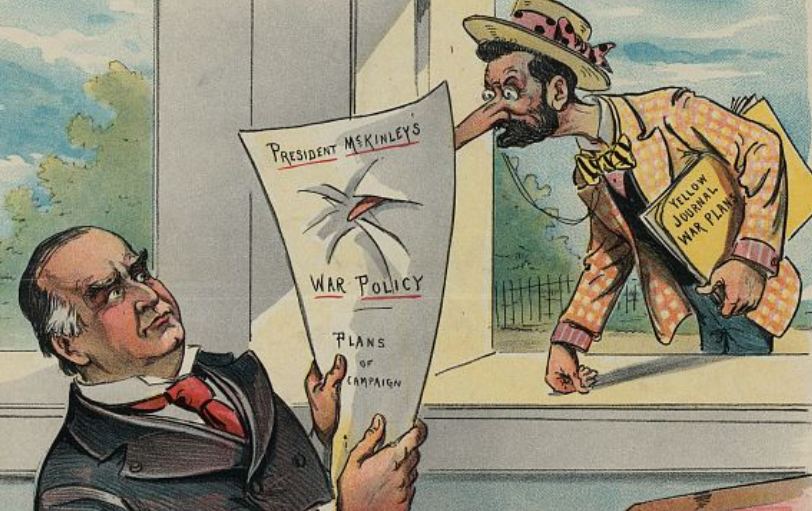 A man carrying papers under his arm labeled Yellow Journal War Plans leans through a window and sticks his extremely long and pointy nose through a paper that says President McKinley's War Policy being read by President William McKinley.