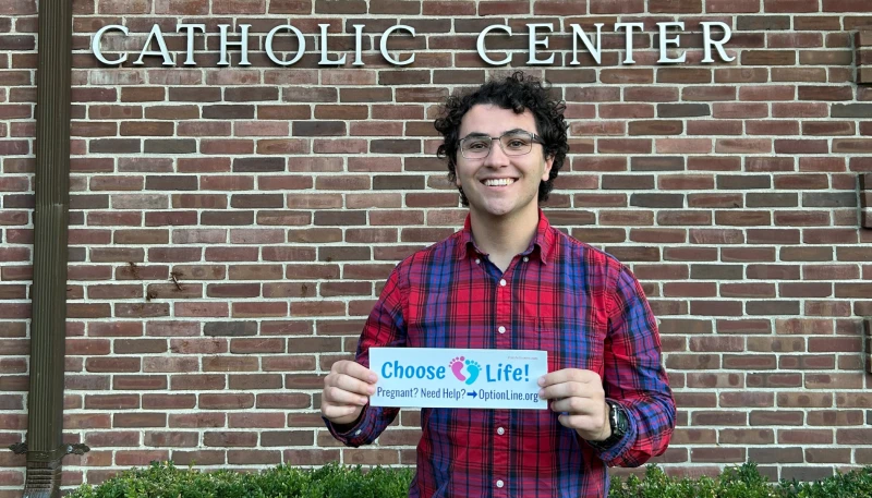 Meet the college student sharing bumper stickers to save unborn lives #Catholic 
 
 Gabriel Dionisi, a 22-year-old college student who makes pro-life bumper stickers with the goal of spreading the pro-life message and spread awareness to others, displays one of his works. / Credit: Gabriel Dionisi

CNA Staff, Nov 10, 2025 / 06:00 am (CNA).
Born and raised Catholic, 22-year-old Gabriel Dionisi always knew that life begins at conception and that it’s wrong to kill an unborn child in the womb. But it wasn’t until he was a teenager that he became more interested in his faith and started to read more Catholic news, which led to him learning more about the abortion issue. Feeling called to do more for the unborn, he created a pro-life ministry using bumper stickers to help spread awareness. “I’d heard the word abortion before, I knew it was a sin, but I didn’t realize how widespread it was,” Dionisi told CNA in an interview. One day at Mass, he read a pamphlet explaining the different abortion procedures and was left “disturbed” after reading about how many unborn babies are dismembered in certain kinds of abortion procedures.He said he was also surprised to hear how many women are pressured into abortion.“I remember being struck by reading about how many women didn’t want to have abortions — felt pressured or coerced or it wasn’t their first choice — and that was also surprising to me because it made me think, ‘OK, we could actually do something about this,’” he said.Gabriel Dionisi’s pro-life bumper sticker rests on an information table with other resources for pregnant women. Credit: Photo courtesy of Kevin JorreyIn 2018 Dionisi decided to create bumper stickers encouraging individuals to “choose life.” For women who might be in crisis pregnancies, the stickers include the URL to Option Line, a website run by Heartbeat International that offers a map of pregnancy resource centers around the country. The site also offers a 24/7 helpline with counselors who speak both English and Spanish.Dionisi explained that he chose to create bumper stickers because they’re inexpensive to print and “there’s such a good return on investment because if you put a bumper sticker on your car and let’s say 20 people see it every day as you drive, you multiply that by 365, that’s over 7,000 a year.”Since launching his pro-life ministry, Dionisi has shared over 10,000 bumper stickers with people in 45 out of the 50 states.Speaking to the importance of defending the unborn, Dionisi said: “It’s foundational. If we want to see our country succeed and thrive, we need to respect that value of equal human dignity.”He added: “The magnitude of the problem is that so many babies are being lost and not just that, but so many women who are being hurt, men who are being hurt, and it affects our whole society when people are just carrying that wound around with them.”Dionisi said he hopes his bumper stickers are helping to spread awareness of the many resources available for pregnant women in need.“I think it’s important to spread this awareness to everybody because you never know when someone in your own life might be going through a situation where they need help,” he said.“The amazing thing about the pro-life movement is that there are so many opportunities for us, just as regular people, to literally save the lives of others. This is especially important as Catholics, because we know that every human being is made in the image of God and has an enormous potential to bring more love into the world.”Dionisi’s free pro-life bumper stickers can be found here.