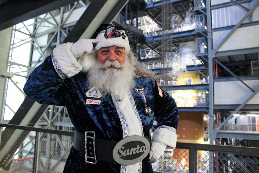 Santa Visits Artemis II Rocket – NASA engineer Guy Naylor poses for a photograph wearing a custom Santa Claus suit on the 19th level of High Bay 4 inside the Vehicle Assembly Building with NASA’s integrated Moon rocket behind him at the agency’s Kennedy Space Center in Florida on Thursday, Dec. 11, 2025.