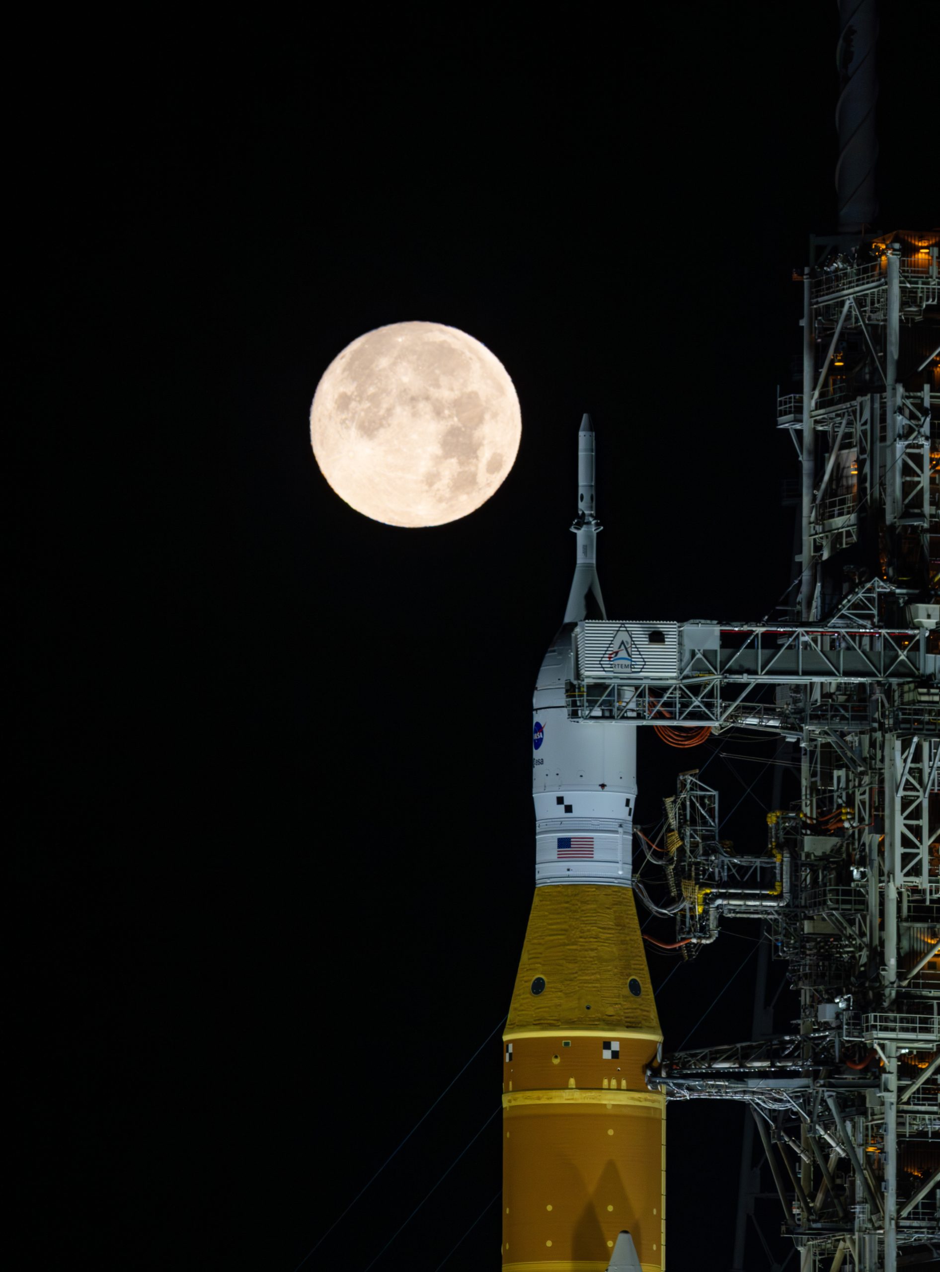 Full Moon over Artemis II – A full moon is seen shining over NASA’s SLS (Space Launch System) and Orion spacecraft, atop the mobile launcher in the early hours of February 1, 2026.