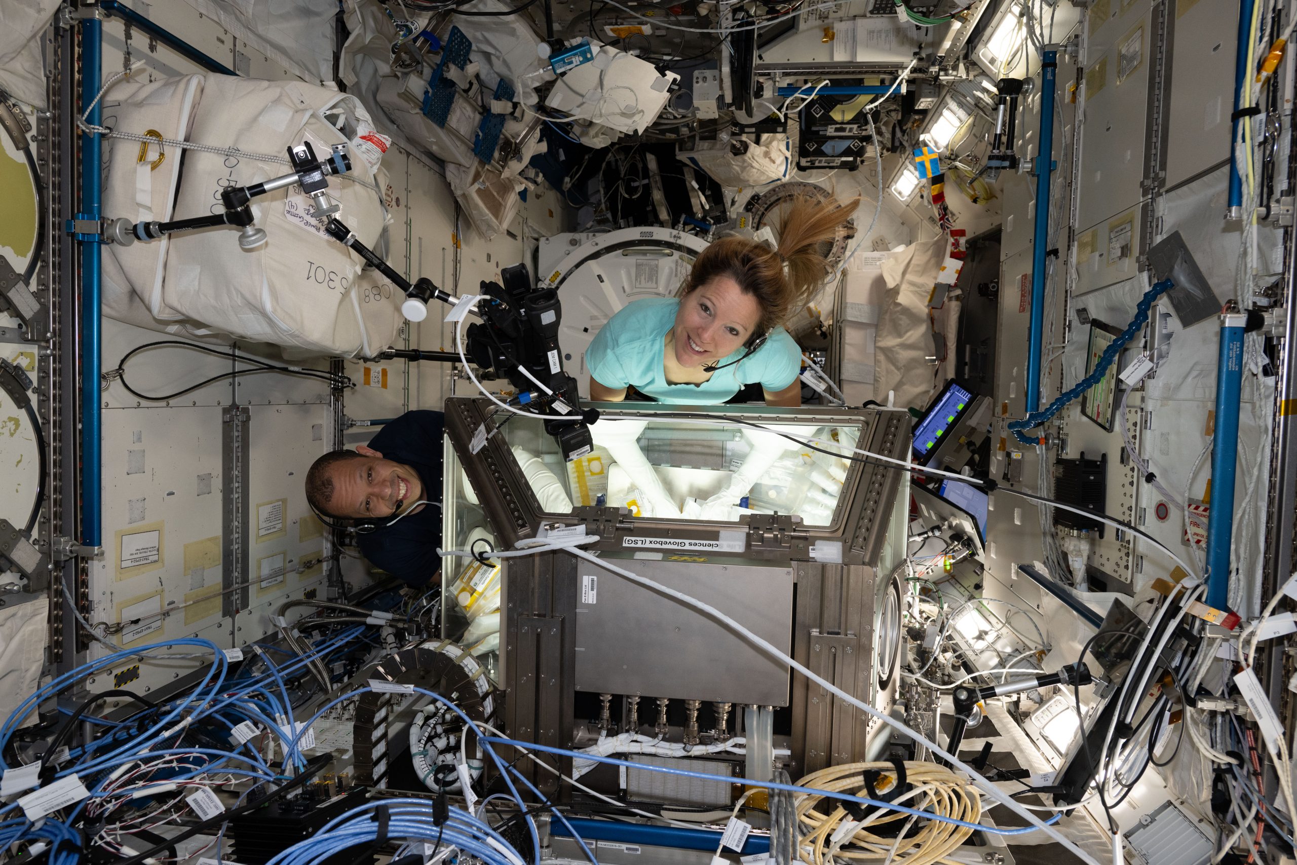 Science in Space – Expedition 74 flight engineers Chris Williams of NASA and Sophie Adenot of the European Space Agency work together in the Kibo laboratory module’s Life Science Glovebox.