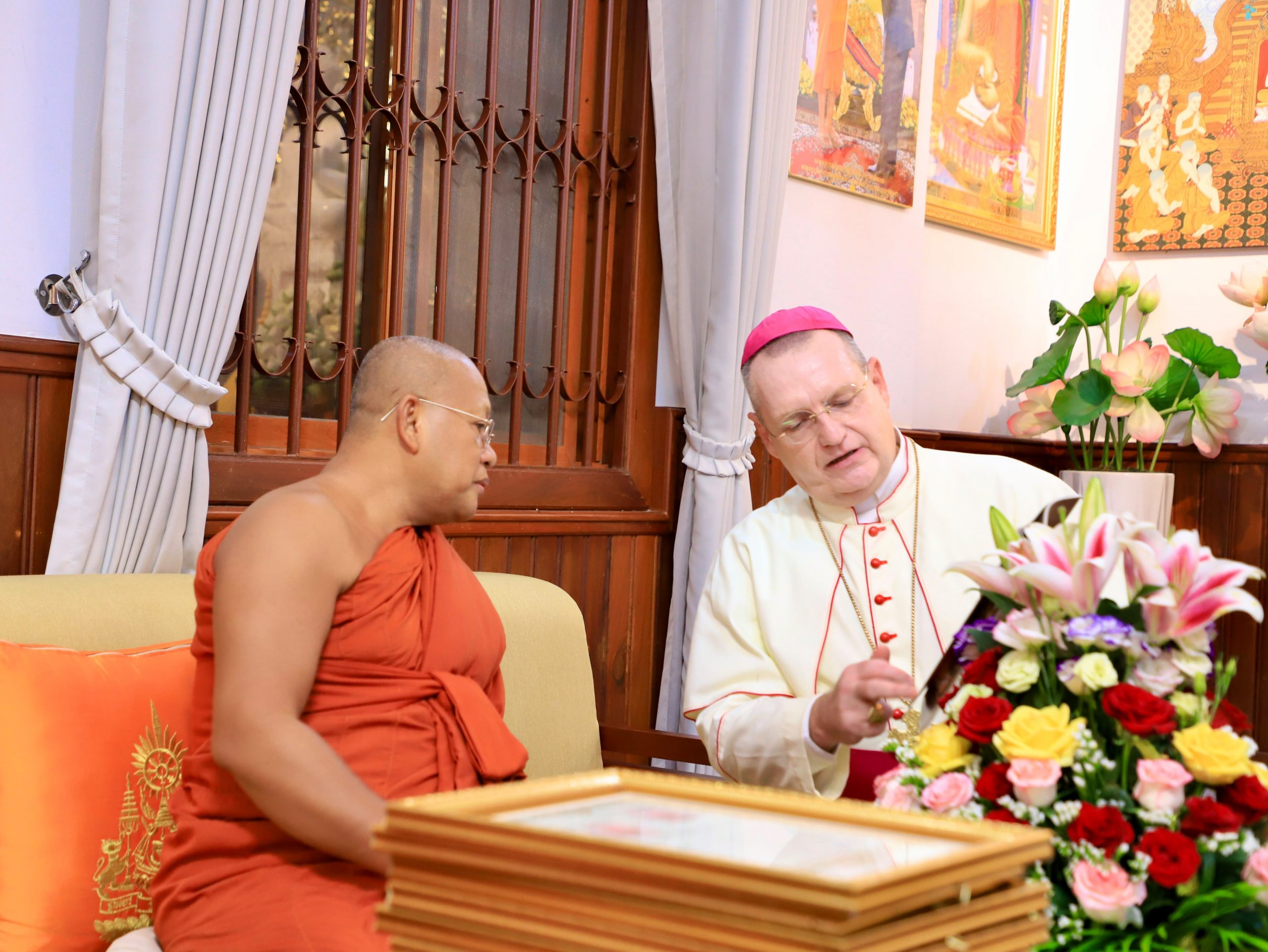 Cambodia’s Buddhist leaders honor Catholic bishop for decades of cooperation #Catholic Cambodia’s Buddhist leadership has conferred a high honorary title on the Catholic bishop of Phnom Penh, recognizing decades of cooperation between Buddhist and Christian communities in a country where the Catholic Church remains a small minority.Bishop Olivier Schmitthaeusler, apostolic vicar of Phnom Penh, received the title “Akka Mahāupāsakabuddhasāsanūpatthambhakr,” roughly translated as “Elder Great Lay Supporter and Upholder of the Buddha’s Dispensation,” during a ceremony on June 13, 2026, at Wat Botum Vatey in the Cambodian capital.
Bishop Olivier Schmitthaeusler meets with Venerable Khim Sorn, third deputy supreme patriarch of Cambodiaʼs Mohanikaya Buddhist order, during a ceremony at Wat Botum Vatey in Phnom Penh on June 13, 2026. | Credit: Ly Sovanna/Catholic National Office for Social Communications in Cambodia
The title was conferred by Supreme Patriarch Nun Nget of Cambodia’s Mohanikaya Buddhist order and presented at a ceremony presided over by Venerable Khim Sorn, the order’s third deputy supreme patriarch.The honor builds on a distinction Schmitthaeusler received in 2022, when Cambodia’s Buddhist leadership named him a “Maha Upasaka,” recognizing his support for Buddhist communities and his role in promoting dialogue and cooperation between Cambodia’s Buddhist majority and its small Catholic minority.At the time, Buddhist leaders cited joint development projects, educational initiatives, and efforts to strengthen social cohesion. The new title represents a higher level of recognition from the country’s Buddhist establishment.Speaking at the ceremony, Khim Sorn pointed to Cambodia’s constitutional framework, which recognizes Buddhism as the state religion while protecting religious freedom.He said the Constitution of the Kingdom of Cambodia clearly stipulates that Buddhism is the state religion, but “it also guarantees complete freedom of religious belief without coercion” and promotes religious harmony, peaceful coexistence, and mutual respect among the different religions.Buddhist leaders said the recognition reflected Schmitthaeusler’s long involvement in educational, humanitarian, and community-development initiatives carried out in cooperation with Buddhist institutions.For Schmitthaeusler, the award marked another chapter in a relationship that began more than two decades ago. “This is a profoundly meaningful event for me as a Catholic bishop,” he said.The French-born missionary of the Paris Foreign Missions Society traced that relationship to his years as a parish priest in Takeo province, where Catholics and Buddhists worked together on local development projects.Among them was the construction of a road linking a Catholic community and a nearby pagoda, an initiative he said helped lay the groundwork for deeper cooperation.Over the years, that collaboration expanded into education and social services. Schmitthaeusler noted that he supported the establishment of a primary school at Wat Ang Montrey, where students study Pali, Sanskrit, and other academic subjects.The prelate also highlighted joint humanitarian efforts during the COVID-19 pandemic and assistance provided to displaced families during recent tensions along the Cambodia-Thailand border.“Receiving the status of Akka Mahāupāsakabuddhasāsanūpatthambhakr today is a moment of profound recognition of how the Catholic Church and Buddhism walk hand-in-hand for the common good of our people and our country,” he said.
Bishop Olivier Schmitthaeusler poses with community members outside Wat Botum Vatey in Phnom Penh on June 13, 2026, after receiving a high honorary title from Cambodiaʼs Buddhist leadership in recognition of his work promoting Buddhist-Christian cooperation. | Credit: Ly Sovanna/Catholic National Office for Social Communications in Cambodia
Schmitthaeusler also cited recent dialogue initiatives involving Buddhist and Christian leaders from Cambodia and across Asia focused on peacebuilding and reconciliation.“We know that when Cambodia is full of peace, it radiates a positive influence to the rest of the world,” he said. “This is a powerful signal: when religions journey together, the world will witness true peace,” he added.A small Church rebuilt after the Khmer RougeTheravada Buddhism is practiced by the vast majority of Cambodia’s roughly 18 million people. The Catholic Church numbers about 20,000 faithful across one apostolic vicariate and two apostolic prefectures.The Catholic Church was nearly wiped out during the Khmer Rouge era, when religious communities were persecuted and most church buildings were destroyed.Since public religious life resumed in the early 1990s, the Catholic Church has gradually rebuilt through education, health care, social services, and pastoral ministry, becoming a small but visible presence in Cambodian society. Cambodia’s Buddhist leaders honor Catholic bishop for decades of cooperation #Catholic Cambodia’s Buddhist leadership has conferred a high honorary title on the Catholic bishop of Phnom Penh, recognizing decades of cooperation between Buddhist and Christian communities in a country where the Catholic Church remains a small minority.Bishop Olivier Schmitthaeusler, apostolic vicar of Phnom Penh, received the title “Akka Mahāupāsakabuddhasāsanūpatthambhakr,” roughly translated as “Elder Great Lay Supporter and Upholder of the Buddha’s Dispensation,” during a ceremony on June 13, 2026, at Wat Botum Vatey in the Cambodian capital.
Bishop Olivier Schmitthaeusler meets with Venerable Khim Sorn, third deputy supreme patriarch of Cambodiaʼs Mohanikaya Buddhist order, during a ceremony at Wat Botum Vatey in Phnom Penh on June 13, 2026. | Credit: Ly Sovanna/Catholic National Office for Social Communications in Cambodia
The title was conferred by Supreme Patriarch Nun Nget of Cambodia’s Mohanikaya Buddhist order and presented at a ceremony presided over by Venerable Khim Sorn, the order’s third deputy supreme patriarch.The honor builds on a distinction Schmitthaeusler received in 2022, when Cambodia’s Buddhist leadership named him a “Maha Upasaka,” recognizing his support for Buddhist communities and his role in promoting dialogue and cooperation between Cambodia’s Buddhist majority and its small Catholic minority.At the time, Buddhist leaders cited joint development projects, educational initiatives, and efforts to strengthen social cohesion. The new title represents a higher level of recognition from the country’s Buddhist establishment.Speaking at the ceremony, Khim Sorn pointed to Cambodia’s constitutional framework, which recognizes Buddhism as the state religion while protecting religious freedom.He said the Constitution of the Kingdom of Cambodia clearly stipulates that Buddhism is the state religion, but “it also guarantees complete freedom of religious belief without coercion” and promotes religious harmony, peaceful coexistence, and mutual respect among the different religions.Buddhist leaders said the recognition reflected Schmitthaeusler’s long involvement in educational, humanitarian, and community-development initiatives carried out in cooperation with Buddhist institutions.For Schmitthaeusler, the award marked another chapter in a relationship that began more than two decades ago. “This is a profoundly meaningful event for me as a Catholic bishop,” he said.The French-born missionary of the Paris Foreign Missions Society traced that relationship to his years as a parish priest in Takeo province, where Catholics and Buddhists worked together on local development projects.Among them was the construction of a road linking a Catholic community and a nearby pagoda, an initiative he said helped lay the groundwork for deeper cooperation.Over the years, that collaboration expanded into education and social services. Schmitthaeusler noted that he supported the establishment of a primary school at Wat Ang Montrey, where students study Pali, Sanskrit, and other academic subjects.The prelate also highlighted joint humanitarian efforts during the COVID-19 pandemic and assistance provided to displaced families during recent tensions along the Cambodia-Thailand border.“Receiving the status of Akka Mahāupāsakabuddhasāsanūpatthambhakr today is a moment of profound recognition of how the Catholic Church and Buddhism walk hand-in-hand for the common good of our people and our country,” he said.
Bishop Olivier Schmitthaeusler poses with community members outside Wat Botum Vatey in Phnom Penh on June 13, 2026, after receiving a high honorary title from Cambodiaʼs Buddhist leadership in recognition of his work promoting Buddhist-Christian cooperation. | Credit: Ly Sovanna/Catholic National Office for Social Communications in Cambodia
Schmitthaeusler also cited recent dialogue initiatives involving Buddhist and Christian leaders from Cambodia and across Asia focused on peacebuilding and reconciliation.“We know that when Cambodia is full of peace, it radiates a positive influence to the rest of the world,” he said. “This is a powerful signal: when religions journey together, the world will witness true peace,” he added.A small Church rebuilt after the Khmer RougeTheravada Buddhism is practiced by the vast majority of Cambodia’s roughly 18 million people. The Catholic Church numbers about 20,000 faithful across one apostolic vicariate and two apostolic prefectures.The Catholic Church was nearly wiped out during the Khmer Rouge era, when religious communities were persecuted and most church buildings were destroyed.Since public religious life resumed in the early 1990s, the Catholic Church has gradually rebuilt through education, health care, social services, and pastoral ministry, becoming a small but visible presence in Cambodian society.