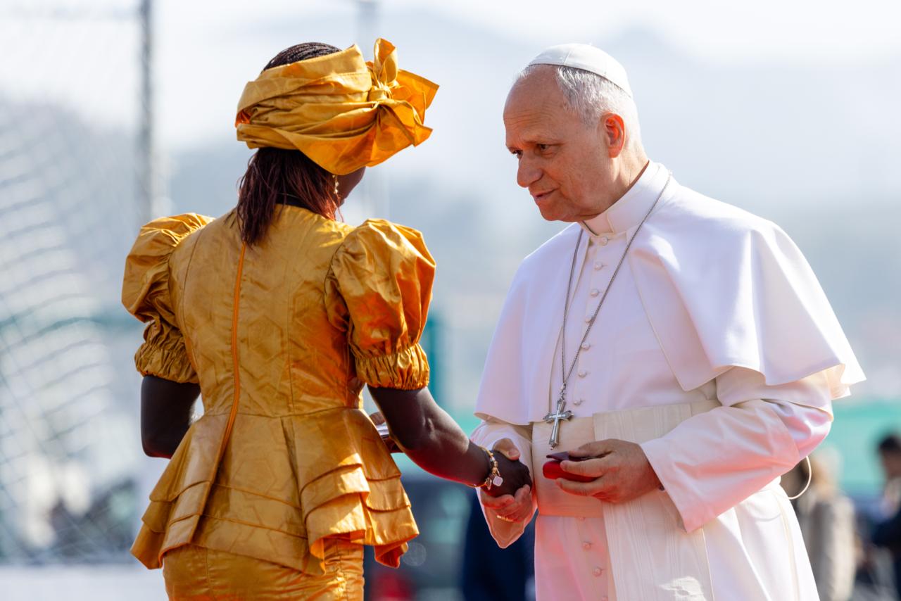 Migrants in Tenerife tell Pope Leo XIV: We do not ask for privileges or compassion #Catholic TENERIFE, Canary Islands — “No one leaves their land, their family and their roots by choice when they can live in peace,” said Bousso Diouf, a woman from Senegal who spoke with the moral authority of someone who risked her life crossing the Atlantic in a wooden boat, knowing the journey could last a week or end adrift at sea.Diouf was among the migrants who greeted Pope Leo XIV at the Las Raíces reception center in Tenerife, where some 700 sub-Saharan African migrants — all adult men — are currently housed. The center is located in the humid Las Raíces area of Tenerife, a eucalyptus-filled area about 3,300 feet above sea level.The number is relatively low compared with the hardest years of the “cayuco” crisis, especially at the end of 2024, when the center received between 2,000 and 3,000 migrants amid overcrowding and widely reported tensions.Most of those currently housed at the center come from Senegal, Gambia, and Mali, and on average spend about three months there before being transferred to mainland Spain.They arrive exhausted after having spent up to 72 hours in police custody for identification and registration procedures.“We come from countries where poverty, violence, war, persecution, and lack of opportunity forced us to leave,” Diouf said.Las Raíces opened in 2021 in response to the 2020 crisis, when more than 23,000 migrants arrived on the coasts of the Canary Islands.Now those numbers have fallen sharply, and the situation is very different.“Our work is to offer them an initial welcome that is dignified, humane, and organized at an especially difficult moment, immediately after their arrival by sea,” Navarro Atiénzar, regional director of Accem, the NGO that manages the Las Raíces Reception Center for Refugees and Immigrants in Tenerife, told Pope Leo.The pope arrived in Tenerife early in the morning from Las Palmas and went to the large camp set up inside a former rural military barracks after six marathon days in Spain that had taken him to Barcelona and Madrid.He listened to those housed there as a father listens when a child opens his heart to recount a trauma.One young Nigerian man said that crossing the ocean to the Canary Islands means facing hunger, cold, desperation, and often death.“Many brothers and sisters lost their lives at sea, and others continue to suffer in silence, victims of mafias that take advantage of need and human suffering,” he said.He also made a plea for humanity: “May we not be seen only as migrants, numbers, or documents, but as people with stories, dreams, families, and hope.”“We do not ask for privileges. We do not ask for compassion. We ask for respect, humanity, and the opportunity to live with dignity,” he said.Among those present was also Aliu Ceesay, a 16-year-old Gambian who arrived in the Canary Islands just one month ago in an irregular boat after a difficult journey from his home country. Like many other migrant minors, his goal is to find work so he can help support his family.Amid an experience marked by uncertainty, Aliu has followed Pope Leo XIV with interest online. The teenager said he wanted to see him in person and was struck by the pope’s message.“I have been following him on the internet and wanted to see him. He is very kind, very good,” Aliu said. He also emphasized the pope’s inclusive spirit: “He does not care if we are black or white, Muslim or Christian. He wants to help us.”More than 54,000 people have passed through Las Raíces. Behind each one is a story, a difficult journey, and, above all, a hope.In his address, Pope Leo repeated the message he gave on the first day he set foot in Las Palmas: “God’s love knows no borders, makes no distinctions, is given to all and brings us together in unity.”“As I look at your faces and listen to your stories, I also think of your hearts — wounded by so many difficulties, yet also comforted by the love you have received from other open, generous and merciful hearts,” the pope said.“Christ’s heart suffered and was pierced out of love, and he was also comforted by compassionate people who eased his pain,” he added.Missionary saints and migrantsThe pope dedicated part of his address to missionary saints such as St. Brother Peter of St. Joseph de Betancur and St. José de Anchieta, who set out from the Canary Islands to proclaim the Gospel in the Americas, opening new missionary horizons.“They too were migrants who ventured into the unknown, carrying faith, hope and charity as their greatest possessions,” he said.The pope called for “responsibility” with an eye toward future generations, to whom, he said, “we wish to bequeath the heritage of a civilization of love.”“Migration will play an important role in this,” he said, because it “can become an opportunity for encounter and mutual enrichment among peoples.”“Dear brothers and sisters, in a sense, all of us are migrants, for we are all pilgrims on our way to our heavenly homeland,” he said. “Let us help make this journey more humane for everyone by contributing in whatever way we can.”The pope said the name of the center, Las Raíces — “the roots” — had caught his attention. He recalled that Pope Francis, “who so longed to be with you,” often used the image of roots “to emphasize the importance of remembering our origins, staying united and trusting in the Lord.”“May this image of roots also help you to be firmly rooted in the Lord, so that no storm may drive you away from his presence, which strengthens and gives life,” Pope Leo said.At the end of his address, the pope told those gathered: “Dear friends, I carry you in my heart and will remember you in my prayers. May God bless you, your families and all who do good to you. And may the Blessed Virgin Mary, Consolation of Migrants, always accompany and assist you with her maternal protection.”During the meeting, when the pope announced that he would speak in French and English, many migrants responded with loud applause.This story was first published by ACI Prensa, the Spanish-language sister service of EWTN News. It has been translated and adapted by EWTN News English. Migrants in Tenerife tell Pope Leo XIV: We do not ask for privileges or compassion #Catholic TENERIFE, Canary Islands — “No one leaves their land, their family and their roots by choice when they can live in peace,” said Bousso Diouf, a woman from Senegal who spoke with the moral authority of someone who risked her life crossing the Atlantic in a wooden boat, knowing the journey could last a week or end adrift at sea.Diouf was among the migrants who greeted Pope Leo XIV at the Las Raíces reception center in Tenerife, where some 700 sub-Saharan African migrants — all adult men — are currently housed. The center is located in the humid Las Raíces area of Tenerife, a eucalyptus-filled area about 3,300 feet above sea level.The number is relatively low compared with the hardest years of the “cayuco” crisis, especially at the end of 2024, when the center received between 2,000 and 3,000 migrants amid overcrowding and widely reported tensions.Most of those currently housed at the center come from Senegal, Gambia, and Mali, and on average spend about three months there before being transferred to mainland Spain.They arrive exhausted after having spent up to 72 hours in police custody for identification and registration procedures.“We come from countries where poverty, violence, war, persecution, and lack of opportunity forced us to leave,” Diouf said.Las Raíces opened in 2021 in response to the 2020 crisis, when more than 23,000 migrants arrived on the coasts of the Canary Islands.Now those numbers have fallen sharply, and the situation is very different.“Our work is to offer them an initial welcome that is dignified, humane, and organized at an especially difficult moment, immediately after their arrival by sea,” Navarro Atiénzar, regional director of Accem, the NGO that manages the Las Raíces Reception Center for Refugees and Immigrants in Tenerife, told Pope Leo.The pope arrived in Tenerife early in the morning from Las Palmas and went to the large camp set up inside a former rural military barracks after six marathon days in Spain that had taken him to Barcelona and Madrid.He listened to those housed there as a father listens when a child opens his heart to recount a trauma.One young Nigerian man said that crossing the ocean to the Canary Islands means facing hunger, cold, desperation, and often death.“Many brothers and sisters lost their lives at sea, and others continue to suffer in silence, victims of mafias that take advantage of need and human suffering,” he said.He also made a plea for humanity: “May we not be seen only as migrants, numbers, or documents, but as people with stories, dreams, families, and hope.”“We do not ask for privileges. We do not ask for compassion. We ask for respect, humanity, and the opportunity to live with dignity,” he said.Among those present was also Aliu Ceesay, a 16-year-old Gambian who arrived in the Canary Islands just one month ago in an irregular boat after a difficult journey from his home country. Like many other migrant minors, his goal is to find work so he can help support his family.Amid an experience marked by uncertainty, Aliu has followed Pope Leo XIV with interest online. The teenager said he wanted to see him in person and was struck by the pope’s message.“I have been following him on the internet and wanted to see him. He is very kind, very good,” Aliu said. He also emphasized the pope’s inclusive spirit: “He does not care if we are black or white, Muslim or Christian. He wants to help us.”More than 54,000 people have passed through Las Raíces. Behind each one is a story, a difficult journey, and, above all, a hope.In his address, Pope Leo repeated the message he gave on the first day he set foot in Las Palmas: “God’s love knows no borders, makes no distinctions, is given to all and brings us together in unity.”“As I look at your faces and listen to your stories, I also think of your hearts — wounded by so many difficulties, yet also comforted by the love you have received from other open, generous and merciful hearts,” the pope said.“Christ’s heart suffered and was pierced out of love, and he was also comforted by compassionate people who eased his pain,” he added.Missionary saints and migrantsThe pope dedicated part of his address to missionary saints such as St. Brother Peter of St. Joseph de Betancur and St. José de Anchieta, who set out from the Canary Islands to proclaim the Gospel in the Americas, opening new missionary horizons.“They too were migrants who ventured into the unknown, carrying faith, hope and charity as their greatest possessions,” he said.The pope called for “responsibility” with an eye toward future generations, to whom, he said, “we wish to bequeath the heritage of a civilization of love.”“Migration will play an important role in this,” he said, because it “can become an opportunity for encounter and mutual enrichment among peoples.”“Dear brothers and sisters, in a sense, all of us are migrants, for we are all pilgrims on our way to our heavenly homeland,” he said. “Let us help make this journey more humane for everyone by contributing in whatever way we can.”The pope said the name of the center, Las Raíces — “the roots” — had caught his attention. He recalled that Pope Francis, “who so longed to be with you,” often used the image of roots “to emphasize the importance of remembering our origins, staying united and trusting in the Lord.”“May this image of roots also help you to be firmly rooted in the Lord, so that no storm may drive you away from his presence, which strengthens and gives life,” Pope Leo said.At the end of his address, the pope told those gathered: “Dear friends, I carry you in my heart and will remember you in my prayers. May God bless you, your families and all who do good to you. And may the Blessed Virgin Mary, Consolation of Migrants, always accompany and assist you with her maternal protection.”During the meeting, when the pope announced that he would speak in French and English, many migrants responded with loud applause.This story was first published by ACI Prensa, the Spanish-language sister service of EWTN News. It has been translated and adapted by EWTN News English.