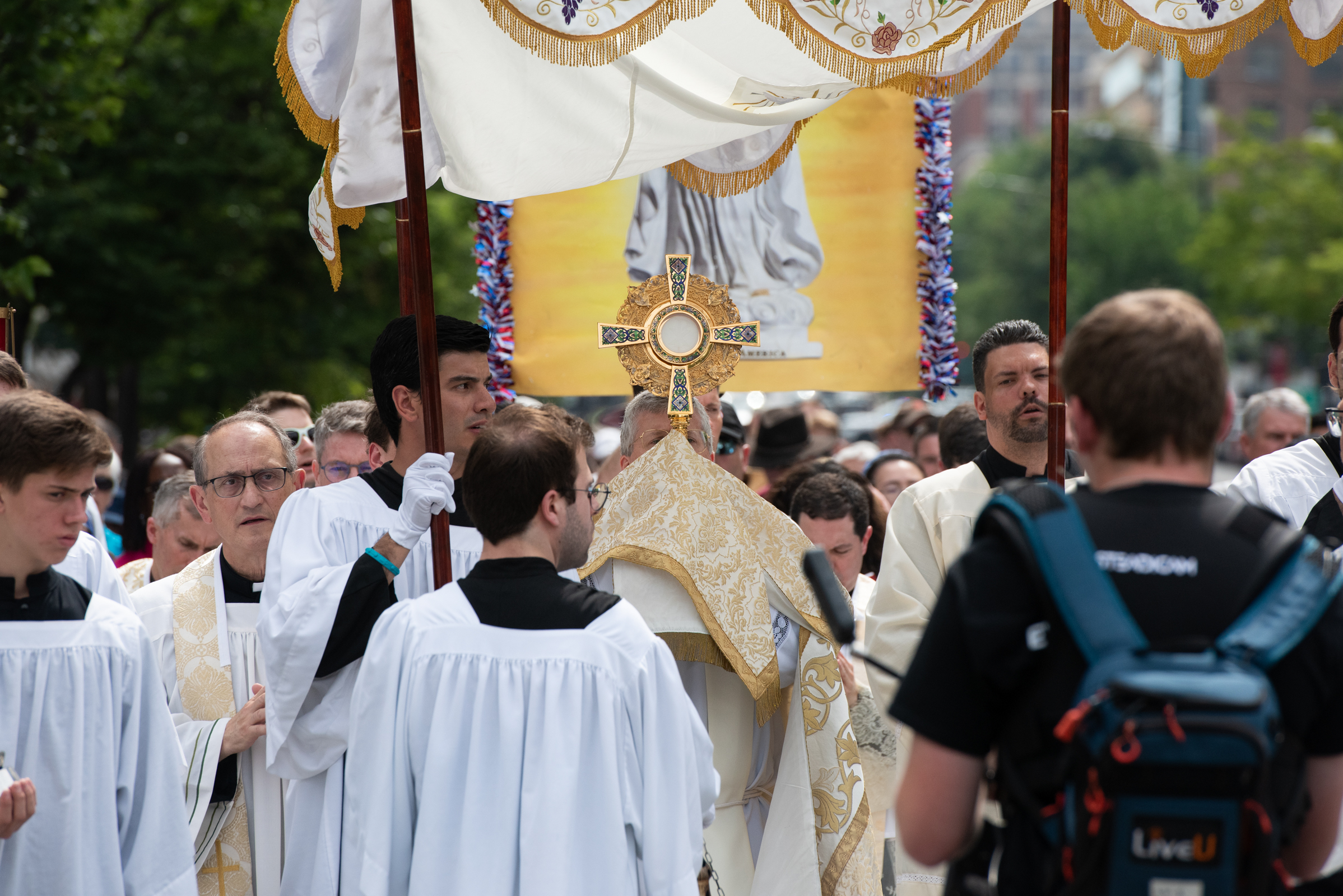 Over 1,000 people process with Jesus Christ in the Eucharist through Washington, D.C. – #Catholic – More than 1,000 people processed through the streets of downtown Washington, D.C. on Saturday morning as the third annual National Eucharistic Pilgrimage made its way through the nation’s capital.“Today we are going to bring Jesus Christ in the Blessed Sacrament to the streets of Washington, D.C.,” Father Charles Trullols, the director of the Catholic Information Center, said in a homily during the June 6 morning Mass before the procession began.The procession offers “public witness to our faith,” Trullols said, displaying “the real presence of Jesus Christ in the Eucharist, body, blood, soul, and divinity” to each person the procession passes by. Dozens of onlookers stopped to watch the procession, with many taking photos and videos.The route began outside the Catholic Information Centerʼs K Street headquarters and went past Lafayette Square, which faces the White House. It also passed Farragut Square, McPherson Square, and the Veterans Affairs building.
 
 The Blessed Sacrament is elevated in a monstrance during a Eucharistic procession in Washington, D.C., just outside of the White House, June 6, 2026. Approximately 1,000 pilgrims processed through downtown Washington carrying the Blessed Sacrament. | Credit: Jeff Bruno / EWTN News
 
 Children who had recently received their First Holy Communion laid flower petals on the ground and the procession was led by cross and candle bearers, followed by religious sisters, the Blessed Sacrament in a monstrance, the priests, the choir, and the lay people.“I think it’s just a great opportunity to be a witness for Christ to a city that is so lost and while we were out there I was praying that someone who was out there would see it and come back to the Lord and find peace in the Lord and Christ,” Katie, from Jacksonville, Florida, told EWTN News.“It’s just a beautiful witness out here today and Iʼm so grateful this was available especially to those who need it,” she said.
 
 Religious sisters pray during a Eucharistic procession in Washington, D.C., June 6, 2026. Approximately 1,000 pilgrims processed through downtown Washington carrying the Blessed Sacrament. | Credit: Jeff Bruno / EWTN News
 
 John, from Maryland, highlighted the significance of processing with the Eucharist in the nation’s capital less than one month before the country celebrates the Fourth of July.“I think it’s very cool that this being the 250th anniversary of America we can do something like this,” he said. “It shows the freedom of religion in this country, and that it’s a great country to be in.”The procession was one stop in the National Eucharistic Pilgrimage, a project of the National Eucharistic Congress that is bringing processions to dioceses across the country. This year’s route focuses mostly on visiting the original 13 colonies of the United States to honor the 250th anniversary of the Declaration of Independence.
 
 Pilgrims follow the Blessed Sacrament during a Eucharistic procession in Washington, D.C., June 6, 2026. Approximately 1,000 pilgrims processed through downtown Washington carrying the Blessed Sacrament. | Credit: Jeff Bruno / EWTN News
 
 Trullols noted in his homily that the pilgrimage theme is “one nation under God,” which he said is “not merely a patriotic slogan,” but an invitation to place our lives, our families, and communities under Christ.A nation under God “does not sustain itself automatically,” Trullols said. Rather, it can only be sustained “if its people choose to place God first.”The Catholic Information Center has held a Eucharistic procession in downtown Washington for four straight years, initially independent of the broader pilgrimage. Trullos told EWTN News that the pilgrimage reached out to the Archdiocese of Washington, D.C., which then reached out to center to partner this year on the procession.“This procession is an expression in our capital for the love of our country and the desire to pray for our people and our nation,” Trullos said.He estimated the attendance was around 1,300 people, noting it’s growing “much bigger” every year they host it.
 
 Acolytes stand by during a Eucharistic procession in Washington, D.C., June 6, 2026. Approximately 1,000 pilgrims processed through downtown Washington carrying the Blessed Sacrament. | Credit: Jeff Bruno / EWTN News
 
 There are nine perpetual pilgrims traveling with the National Eucharistic Pilgrimage for the entire journey, which began in St. Augustine, Florida less than two weeks ago and will conclude in Philadelphia, Pennsylvania on the Fourth of July weekend.Mary Carmen Zakrajsek, a perpetual pilgrim originally from Carmel, Indiana, said in a news conference after the procession that bringing the Eucharist into the streets has captivated people who encounter it: “Jesus walked this earth and he’s walking it again. He has not abandoned us.”Zakrajsek called the pilgrimage a “unifying moment” and echoed the language in the Declaration of Independence that rights are endowed by our creator.“Our moral authority does not come from the State,” she said. “It comes from God.”
