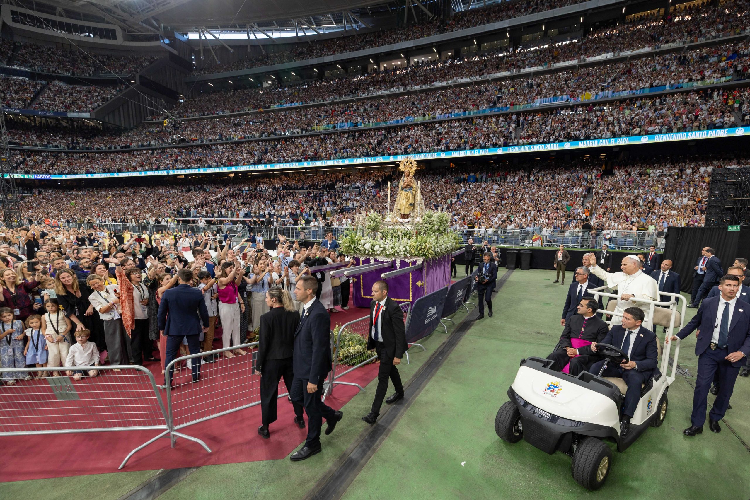 Pope Leo scores goal for the Gospel at soccer stadium - #Catholic - Before a packed Santiago Bernabéu stadium and a crowd fully swept up in the moment, a figure dressed in white made his entrance. Yet it was neither Mbappé nor Cristiano Ronaldo nor any other Real Madrid soccer team legend but Leo XIV.It was a particularly significant moment for the pope at the arena where the team he loves — though, as pontiff, he’s for everyone — has achieved its greatest sporting feats. No match was being played, but the faithful of the Archdiocese of Madrid, together with the suffragan dioceses of Alcalá de Henares and Getafe, welcomed Leo with a euphoria comparable to that of a decisive goal in a World Cup final.
 
 Pope Leo blessing a child at the Santiago Bernabéu stadium in Madrid, June 8, 2026. | Credit: Daniel Ibañez/EWTN News
 
 “For a soccer player, scoring a goal in this stadium is a moment that leaves a bit of a mark on your life. Today, the Church in Madrid has scored a spectacular goal for all time," the pope said before beginning his address.The event brought together representatives from parishes, movements, and consecrated life, as well as priests and pastoral workers, with a special presence from parish pastoral councils. Young people performed a short play for the pope modeled after a soccer match, and David Bustamante, a famous Spanish singer, also performed. There were also deeply moving personal testimonies, such as that of a 33-year-old man who shared with the gathering that he had been baptized last year and is now preparing to get married.
 
 The event brought together representatives from parishes, movements, and consecrated life, as well as priests and pastoral workers, with a special presence from parish pastoral councils. | Credit: Daniel Ibáñez/EWTN News
 
 When he addressed the priests, consecrated persons, and bishops of Madrid, the pope told them: “Your joy will be contagious if, moving from being just a fleeting emotion, it becomes a stable way of being, a deep sentiment that renews individuals, groups, and the diocesan community.”“Baptism truly changes one’s life ... thereʼs no need to fear the fact that it never produces uniformity,” the pontiff stated during his second to last gathering in the Spainʼs capital city, prior to beginning the second leg of his journey, which will take him to Barcelona on Tuesday, June 9.To illustrate this idea, he referenced the New Testament as an antidote to uniformity, thanks to the “testimony of the variety of its voices.” He also drew attention to the episode of the Tower of Babel, where, according to the biblical account, people in a "totalitarian and merely human project ended up unable to understand their neighbor.”In contrast to this, and in line with the proposals in his recent encyclical Magnifica humanitas, he presented the figure of Nehemiah who involved the entire community in rebuilding the walls of Jerusalem.
 
 “Seeking and following him is the condition for proclaiming him,” said the Pope about the task of evangelization. | Credit: Vatican Media
 
 The pope used this gathering with some of the faithful of the diocesan community in the Madrid region to outline the keys to effective evangelization in the twenty-first century. He emphasized the importance of “not scattering or shutting ourselves away in the group or environment where we already feel secure among people who always sing the same tune.”“To reach the heart of the city, we must cultivate the awareness that truth is symphonic and always transcends us, and cultivate the desire to encounter the Risen One, who always goes ahead of us, preceding us and perhaps already present where we have not yet sought him,” he noted.Therefore, he continued, “seeking and following him is the condition for proclaiming him; otherwise, there is no evangelization, and today we can understand this better than in the past.”Quoting St. Teresa of Avila, he said, “‘Let nothing trouble you, let nothing frighten you!’ Together, as a diocesan Church, you can offer the Gospel witness that unleashes the best strengths of a humanity bombarded by images and words, yet hungry for justice and thirsty for truth,” he added.He also highlighted the special relationship between the Church and the city, which, as he explained, takes shape “among flesh-and-blood people, in workplaces and close relationships, but also within the different communities, associations, and neighborhood organizations,” and which gains even greater significance “amidst the change of epochs we are currently experiencing.”“When we reduce ecclesial life to a routine where everyone remains locked within their own habits and roles, what we lack is the Spirit,” he stated.His words seemed to resonate in the testimony of Sister María San José of the Congregation of the Daughters of Holy Mary of the Heart of Jesus. She is an educated, independent woman with two careers and two masterʼs degrees who left a comfortable life at Santander Bank to consecrate herself to religious life, demonstrating how God’s call reaches into every walk of life.“I realized that there was something more that fulfilled me — beyond everything I had and everything I had built — and that was this consecrated life, this total dedication to the Lord,” she explained to EWTN News while on her way to the gathering.“God knows the hearts of his people individually. He knows them as only he can — that is, in love and, therefore, in freedom,” the pope said, underscoring that God is “infinite mercy and wants everyone to be saved.” “He desires this to the point of becoming flesh and taking upon himself all the sin, evil, and negativity of the world,” he emphasized.Among those present at Bernabéu stadium was Father Antonio Sánchez, a priest of the Diocese of Getafe ordained last October. He shared with ACI Prensa, the Spanish-language sister service of EWTN News, the deep emotion he felt participating along with the pope in the Corpus Christi procession following the Mass celebrated in the Plaza de Cibeles on Sunday, June 7.
 
 Father Antonio Sánchez at Bernabéu Stadium on June 8, 2026. | Credit: Courtesy of Father Antonio Sánchez.
 
 It was, in his words, “a privilege to be selected without any merit; all they said was that the priests of the ecclesiastical province should be at the procession,” he explained.“With an attitude of adoration, seeing the pope who was a great witness, because being close to the procession during such a unique moment was truly special. We were on the same [ground] level as the pope, and seeing him in the procession, adoring and focused on Christ ... it was a moment of realization: amidst all the commotion, we were focused on Christ, to whom we have consecrated our lives,” he told ACI Prensa shortly before the pontiff entered the stadium where he was welcomed with tremendous enthusiasm. Prior to this gathering, the pope visited Santa María la Real de la Almudena Cathedral, which became the setting for one of his most touching moments in Madrid.The Holy Father placed the Golden Rose at the feet of the image of the Virgin of Almudena as a symbol of his filial love, a gesture reflecting the pope’s deep Marian devotion. This marks the fourth Spanish image of the Virgin to receive this gift; the other three are the Virgin of Hope Macarena, the Virgin of La Cabeza and the Virgin of Montserrat.
 
 Pope Leo XIV at the Almudena Cathedral on June 8, 2026. Credit: Vatican Media
 
 This pontifical distinction is a recognition of the popular piety and Marian devotion of Madrid. It has ancient roots and symbolizes the papal blessing.The tradition dates back to Pope Leo IX, who established it in 1049. Over the centuries, it has been bestowed upon monasteries, shrines, sovereigns, and prominent figures in recognition of their commitment to the faith and the common good. In the past, the Golden Rose was also awarded to queens, including Isabella the Catholic Monarch, who was the first queen to receive it in 1493, granted by Innocent VIII.In the solemn act, Pope Leo climbed the steps leading to the base of the image to lay the floral offering and pray. His most notable previous visit to the Almudena Cathedral took place on the occasion of the 2002 canonization of Alonso de Orozco, an Augustinian who died in Madrid, in the convent that occupied the site of the current Senate building. The saint’s remains now rest in the chapel of the Contemplative Augustinian Nuns’ convent on La Granja street.This story was first published by ACI Prensa, the Spanish-language sister service of EWTN News. It has been translated and adapted by EWTN News English.