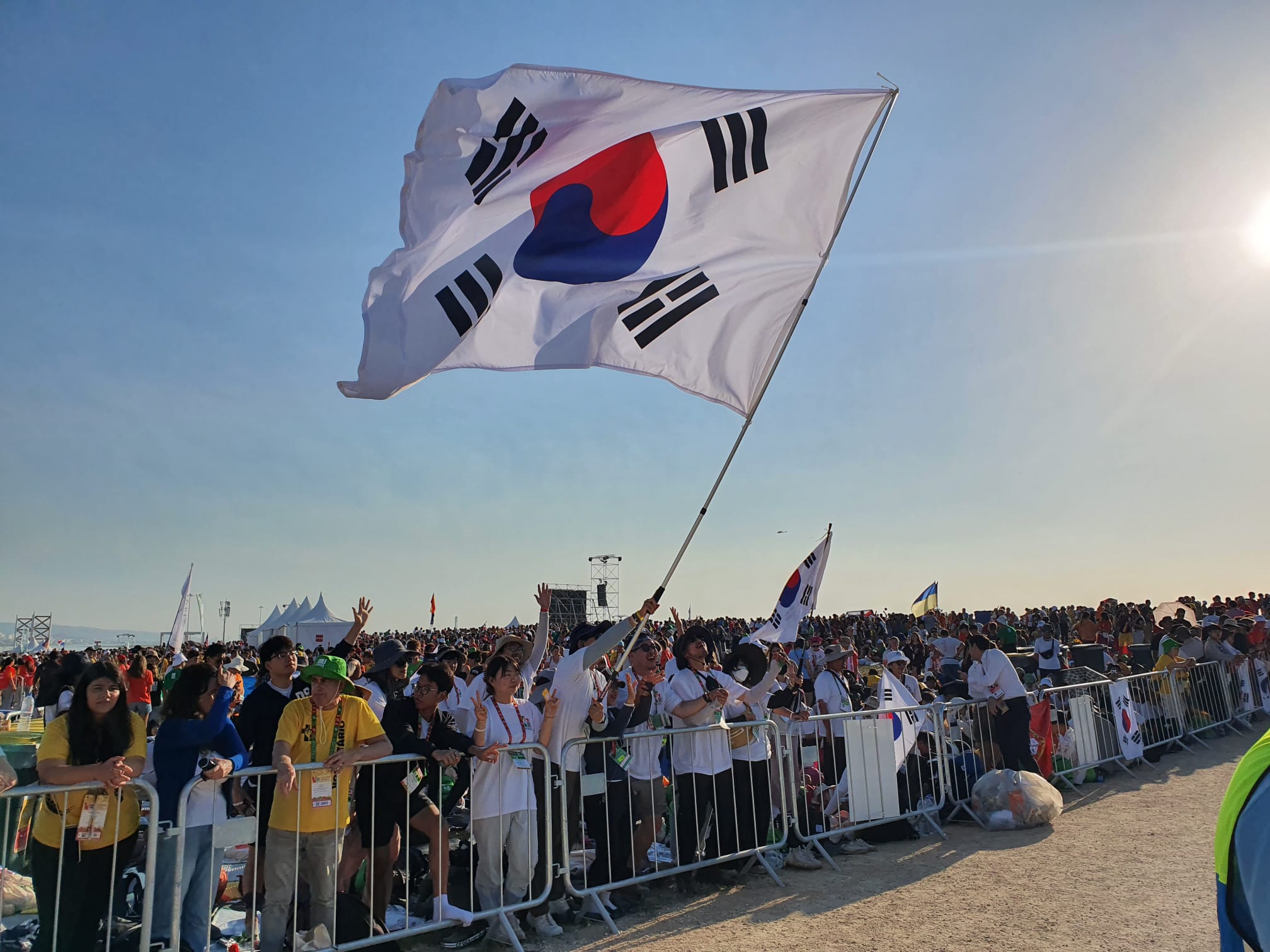 Official Seoul World Youth Day song to be released Aug. 3 – #Catholic – With roughly one year to go before World Youth Day (WYD) in Seoul, South Korea, in 2027, organizers have announced the launch dates for its official theme song. In a July 30 press release, the local organizing committee announced the start of the event’s implementation phase, continuing preparations for services to welcome pilgrims.Pope Leo XIV will also attend the global event, to be held Aug. 3–8, 2027. His attendance will continue the trend of a regular papal presence at WYD since St. John Paul II established it in 1985. WYD 2027 will be the first WYD to be celebrated in a non-Christian country and only the second in Asia.Theme song and tree-planting campaign to launch Aug. 3On Aug. 3, the WYD 2027 countdown will begin, and its official theme song will premiere on its official YouTube channel. The song, “Confidite, Ego Vici Mundum” (“Take Courage! I Have Overcome the World,” in Latin), was the winning composition from 434 submissions and was written by Korean composer Francis Jiyoon Kim.
Pilgrims hold the WYD Seoul 2027 flag at the Presidente Nicolau Lobato International Airport (DIL) in Dili, Timor-Leste, on Aug. 23, 2025. | Credit: WYD Seoul 2027 Local Organizing Committee.
That same day, the Breath of Life Global Tree-Planting Campaign will launch, inspired by Pope Francis’ encyclical Laudato Si’. The campaign will encourage young people to practice ecological stewardship in line with the vision laid out in that encyclical.The registration window for WYD 2027 will open in the latter half of 2026, offering pilgrims accommodation, meals, transportation, and insurance services. Volunteers will also be able to register at that time.WYD 2027: A celebration of Korean hospitalityIn the press release, Archbishop Peter Soon-taick Chung of Seoul, president of the local organizing committee, expressed hope that the hundreds of thousands of pilgrims expected in Seoul will experience the hospitality of the South Korean people.“We will do everything possible to make WYD Seoul 2027 a celebration of hope and a witness to the hospitality and solidarity of Korea and Seoul,” Chung said in the release.“Over the past three years, we have concentrated on laying the foundations for the event. The year ahead will be the time to complete our preparations and welcome young people from every part of the world.” Official Seoul World Youth Day song to be released Aug. 3 – #Catholic – With roughly one year to go before World Youth Day (WYD) in Seoul, South Korea, in 2027, organizers have announced the launch dates for its official theme song. In a July 30 press release, the local organizing committee announced the start of the event’s implementation phase, continuing preparations for services to welcome pilgrims.Pope Leo XIV will also attend the global event, to be held Aug. 3–8, 2027. His attendance will continue the trend of a regular papal presence at WYD since St. John Paul II established it in 1985. WYD 2027 will be the first WYD to be celebrated in a non-Christian country and only the second in Asia.Theme song and tree-planting campaign to launch Aug. 3On Aug. 3, the WYD 2027 countdown will begin, and its official theme song will premiere on its official YouTube channel. The song, “Confidite, Ego Vici Mundum” (“Take Courage! I Have Overcome the World,” in Latin), was the winning composition from 434 submissions and was written by Korean composer Francis Jiyoon Kim.
Pilgrims hold the WYD Seoul 2027 flag at the Presidente Nicolau Lobato International Airport (DIL) in Dili, Timor-Leste, on Aug. 23, 2025. | Credit: WYD Seoul 2027 Local Organizing Committee.
That same day, the Breath of Life Global Tree-Planting Campaign will launch, inspired by Pope Francis’ encyclical Laudato Si’. The campaign will encourage young people to practice ecological stewardship in line with the vision laid out in that encyclical.The registration window for WYD 2027 will open in the latter half of 2026, offering pilgrims accommodation, meals, transportation, and insurance services. Volunteers will also be able to register at that time.WYD 2027: A celebration of Korean hospitalityIn the press release, Archbishop Peter Soon-taick Chung of Seoul, president of the local organizing committee, expressed hope that the hundreds of thousands of pilgrims expected in Seoul will experience the hospitality of the South Korean people.“We will do everything possible to make WYD Seoul 2027 a celebration of hope and a witness to the hospitality and solidarity of Korea and Seoul,” Chung said in the release.“Over the past three years, we have concentrated on laying the foundations for the event. The year ahead will be the time to complete our preparations and welcome young people from every part of the world.”