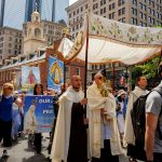 Procesión lleva la Eucaristía al corazón de Boston #Catholic – BOSTON (OSV News) — Fue una vista que, si hubieran vivido para verla, habría hecho que los puritanos de la época colonial escupieran sus frijoles y bacalao.
Más de 2.500 católicos, unidos y orgullosos de su fe, marchando por Boston y llevando la presencia real de Jesús en la Eucaristía a todos en su entorno, liderados por su arzobispo y decenas de sacerdotes, rezando el rosario en un lugar donde la celebración de la Misa era ilegal.
La procesión eucarística de 2.5 millas, que tuvo lugar el 27 de junio como parte de la Peregrinación Eucarística Nacional, fue una celebración del 250 aniversario de los EE.UU. y la historia de Boston. La procesión siguió aproximadamente el Freedom Trail, una especie de ruta de peregrinación que honra el pasado revolucionario de Boston. El tema de la peregrinación nacional a lo largo de la Costa Este del país es “One Nation Under God”.
En Boston Common en la mañana del 27 de junio, los guías turísticos deambulaban en trajes coloniales, rodeados de multitudes masivas que habían venido a adorar al Santísimo Sacramento: sacerdotes en sotanas y gorras de béisbol, hombres y mujeres religiosos en hábitos, multitudes de feligreses que habían llegado en autobuses, y músicos con tambores y guitarras.
Para suscribirse a nuestro boletín electrónico semanal, haga click aquí.
La muestra de solidaridad internacional fue suficiente para rivalizar con la Copa del Mundo. Las comunidades hispana, portuguesa, brasileña, vietnamita, caboverdiana y coreana de la Arquidiócesis de Boston, entre otras, mostraron con orgullo pancartas que honraban a sus países de origen, parroquias y santos patrones.
“Dios los bendiga a todos, Dios bendiga a la ciudad de Boston, Dios bendiga al Commonwealth de Massachusetts y Dios bendiga a América”, dijo el arzobispo Richard G. Henning, dando la bienvenida a los peregrinos.
Les dijo que, mientras caminaban por algunos de los sitios más históricos de los EE.UU., ellos mismos harían historia. Los animó a rezar por la nación.
“Hoy somos testigos”, dijo. “Somos testigos de la gracia y la misericordia de Jesucristo”.
Una multitud de personas se separó para que la Eucaristía, sombreada bajo un dosel bordado, pudiera llegar al arzobispo. La custodia dorada brillaba al sol. La procesión se dirigió hacia la Casa del Estado, una gran masa curva de personas. Algunos cantaban, otros guardaban un silencio reverente. Miembros de las muchas comunidades étnicas de la arquidiócesis proporcionaron música.
La procesión pasó por el Memorial Robert Gould Shaw, luego bajó la colina a través del Common. Una hermana salió de la multitud para ofrecer comida a un hombre sin hogar que descansaba bajo un árbol. El humo del incienso se mezclaba con el vapor que salía de las tapas de las alcantarillas.
La procesión pasó por la Old South Meeting House, donde se organizó el Boston Tea Party; la Old State House, que fue testigo de la Masacre de Boston; el Ayuntamiento; y la Casa de Paul Revere. Una niebla que soplaba teñía las puntas de los rascacielos que se alzaban sobre los monumentos históricos.
El arzobispo Henning y los peregrinos se detuvieron brevemente para adorar al Santísimo Sacramento frente a la Iglesia del Sagrado Corazón en el North End –el arzobispo celebraría más tarde ese día una Misa Votiva del Sagrado Corazón en la Catedral de la Santa Cruz.
“La Iglesia en América ha sido tan importante para el viaje americano”, dijo Mark Riley, quien vino de Amesbury, Massachusetts, para unirse a la procesión. “Piensas en la Iglesia y los Estados Unidos, ambas son fuerzas poderosas para el bien, mejorando el mundo de manera tan hermosa, pero también pasando por tiempos difíciles y luchando contra las dificultades que se presentan en el camino, y por eso estoy aquí. Tierra de los libres, hogar de los valientes”.
Riley nunca había caminado por el Freedom Trail antes. Su amigo Peter Mercier, de Salem, señaló que Riley ahora lo estaba caminando con Jesús.
“Toda la Iglesia es mi vida, realmente”, dijo Mercier.
Al crecer, había tres héroes en su hogar: el Papa San Juan Pablo II, la Madre Teresa y (la estrella del basketball) Larry Bird.
“Es un día hermoso, hermoso, hermoso”, dijo. “Tantas personas fieles aquí. Somos muy afortunados de ser parte de ello, y el arzobispo Henning lo está liderando, y realmente siento que es un gran renacimiento para la fe en Boston y en Nueva Inglaterra”.
La procesión se abrió camino por las estrechas y sinuosas calles del North End, llenas de grupos de turistas y restaurantes italianos. Un hombre con el equipo completo de los Yankees se persignó al ver la procesión. El USS Constitution y el Monumento a Bunker Hill, el destino final de la procesión, eran visibles a través del puerto.
Turistas, trabajadores de la construcción, trabajadores de saneamiento, empresarios, ciclistas, jugadores de softball y personas tomando el sol se detuvieron para ver a los peregrinos. Extendiendo por cuadras a la distancia, las multitudes rezando cruzaron el Puente Bill Russell hacia Charlestown. Un barco llamado “Indiscretion” de Newport, que llevaba una despedida de soltera, tocó su bocina en saludo. Las mujeres a bordo saludaron a los peregrinos. Pasando por la Iglesia de Santa María en Charlestown, la procesión finalmente subió por Monument Avenue hasta el obelisco de 221 pies de altura, donde se había instalado un altar.
“Lo logramos”, dijo el arzobispo Henning ante los aplausos.
Y agregó: “Han hecho algo hermoso. Han dado testimonio de su fe en Jesucristo. Nos hemos unido, hemos rezado, honrando las promesas del pasado y rezando por las esperanzas del futuro”.
Recordó las famosas palabras del puritano John Winthrop, quien instó a sus compañeros colonos a hacer de Boston “una ciudad sobre una colina”, una imagen del Evangelio de Mateo. Generaciones después, en Bunker Hill, los patriotas lucharon contra los británicos. El arzobispo dijo que dieron testimonio de “la libertad y de una visión de la dignidad de cada persona, igual ante Dios”.
“Honramos sus sacrificios y su visión”, dijo. “También estamos llamados a ser la luz, a dar ejemplo, a señalar la verdad de Dios”.
Los fieles se arrodillaron en el césped para adorar al Santísimo Sacramento. Cantaron himnos de alabanza, seguidos de “God Bless America”.
Finalmente, Dominic Smethurst, un estudiante de cuarto grado en la Escuela St. Mary of the Annunciation en Danvers, leyó su poema “Mission Faith” para la multitud.
Dominic ganó un concurso de poesía organizado por la Oficina de Escuelas Católicas de la Arquidiócesis de Boston en honor a la Peregrinación Eucarística Nacional. Se pidió a los estudiantes que reenmarcaran “Paul Revere’s Ride” de Longfellow como “The Midnight Ride of Faith”. Las palabras del poema de Dominic debieron resonar con los peregrinos que habían viajado desde Boston Common hasta Bunker Hill.
“Comienzo mi ruta”, dice su poema. “Vago por la ciudad. Predico mi mensaje, y nunca me desanimo. La ruta es dura, pero tengo fe. Siempre me mantengo firme, porque estoy listo. Predico a todos, ‘¡Ten fe en Dios! ¡Ten esperanza en la vida! ¡Ten coraje para resolver cada conflicto!’ ”
Este artículo fue publicado originalmente (en inglés y español) por The Pilot, el medio informativo de la Arquidiócesis de Boston, y distribuido a través de una colaboración con OSV News. Wes Cipolla forma parte del equipo de The Pilot. Procesión lleva la Eucaristía al corazón de Boston #Catholic – BOSTON (OSV News) — Fue una vista que, si hubieran vivido para verla, habría hecho que los puritanos de la época colonial escupieran sus frijoles y bacalao.
Más de 2.500 católicos, unidos y orgullosos de su fe, marchando por Boston y llevando la presencia real de Jesús en la Eucaristía a todos en su entorno, liderados por su arzobispo y decenas de sacerdotes, rezando el rosario en un lugar donde la celebración de la Misa era ilegal.
La procesión eucarística de 2.5 millas, que tuvo lugar el 27 de junio como parte de la Peregrinación Eucarística Nacional, fue una celebración del 250 aniversario de los EE.UU. y la historia de Boston. La procesión siguió aproximadamente el Freedom Trail, una especie de ruta de peregrinación que honra el pasado revolucionario de Boston. El tema de la peregrinación nacional a lo largo de la Costa Este del país es “One Nation Under God”.
En Boston Common en la mañana del 27 de junio, los guías turísticos deambulaban en trajes coloniales, rodeados de multitudes masivas que habían venido a adorar al Santísimo Sacramento: sacerdotes en sotanas y gorras de béisbol, hombres y mujeres religiosos en hábitos, multitudes de feligreses que habían llegado en autobuses, y músicos con tambores y guitarras.
Para suscribirse a nuestro boletín electrónico semanal, haga click aquí.
La muestra de solidaridad internacional fue suficiente para rivalizar con la Copa del Mundo. Las comunidades hispana, portuguesa, brasileña, vietnamita, caboverdiana y coreana de la Arquidiócesis de Boston, entre otras, mostraron con orgullo pancartas que honraban a sus países de origen, parroquias y santos patrones.
“Dios los bendiga a todos, Dios bendiga a la ciudad de Boston, Dios bendiga al Commonwealth de Massachusetts y Dios bendiga a América”, dijo el arzobispo Richard G. Henning, dando la bienvenida a los peregrinos.
Les dijo que, mientras caminaban por algunos de los sitios más históricos de los EE.UU., ellos mismos harían historia. Los animó a rezar por la nación.
“Hoy somos testigos”, dijo. “Somos testigos de la gracia y la misericordia de Jesucristo”.
Una multitud de personas se separó para que la Eucaristía, sombreada bajo un dosel bordado, pudiera llegar al arzobispo. La custodia dorada brillaba al sol. La procesión se dirigió hacia la Casa del Estado, una gran masa curva de personas. Algunos cantaban, otros guardaban un silencio reverente. Miembros de las muchas comunidades étnicas de la arquidiócesis proporcionaron música.
La procesión pasó por el Memorial Robert Gould Shaw, luego bajó la colina a través del Common. Una hermana salió de la multitud para ofrecer comida a un hombre sin hogar que descansaba bajo un árbol. El humo del incienso se mezclaba con el vapor que salía de las tapas de las alcantarillas.
La procesión pasó por la Old South Meeting House, donde se organizó el Boston Tea Party; la Old State House, que fue testigo de la Masacre de Boston; el Ayuntamiento; y la Casa de Paul Revere. Una niebla que soplaba teñía las puntas de los rascacielos que se alzaban sobre los monumentos históricos.
El arzobispo Henning y los peregrinos se detuvieron brevemente para adorar al Santísimo Sacramento frente a la Iglesia del Sagrado Corazón en el North End –el arzobispo celebraría más tarde ese día una Misa Votiva del Sagrado Corazón en la Catedral de la Santa Cruz.
“La Iglesia en América ha sido tan importante para el viaje americano”, dijo Mark Riley, quien vino de Amesbury, Massachusetts, para unirse a la procesión. “Piensas en la Iglesia y los Estados Unidos, ambas son fuerzas poderosas para el bien, mejorando el mundo de manera tan hermosa, pero también pasando por tiempos difíciles y luchando contra las dificultades que se presentan en el camino, y por eso estoy aquí. Tierra de los libres, hogar de los valientes”.
Riley nunca había caminado por el Freedom Trail antes. Su amigo Peter Mercier, de Salem, señaló que Riley ahora lo estaba caminando con Jesús.
“Toda la Iglesia es mi vida, realmente”, dijo Mercier.
Al crecer, había tres héroes en su hogar: el Papa San Juan Pablo II, la Madre Teresa y (la estrella del basketball) Larry Bird.
“Es un día hermoso, hermoso, hermoso”, dijo. “Tantas personas fieles aquí. Somos muy afortunados de ser parte de ello, y el arzobispo Henning lo está liderando, y realmente siento que es un gran renacimiento para la fe en Boston y en Nueva Inglaterra”.
La procesión se abrió camino por las estrechas y sinuosas calles del North End, llenas de grupos de turistas y restaurantes italianos. Un hombre con el equipo completo de los Yankees se persignó al ver la procesión. El USS Constitution y el Monumento a Bunker Hill, el destino final de la procesión, eran visibles a través del puerto.
Turistas, trabajadores de la construcción, trabajadores de saneamiento, empresarios, ciclistas, jugadores de softball y personas tomando el sol se detuvieron para ver a los peregrinos. Extendiendo por cuadras a la distancia, las multitudes rezando cruzaron el Puente Bill Russell hacia Charlestown. Un barco llamado “Indiscretion” de Newport, que llevaba una despedida de soltera, tocó su bocina en saludo. Las mujeres a bordo saludaron a los peregrinos. Pasando por la Iglesia de Santa María en Charlestown, la procesión finalmente subió por Monument Avenue hasta el obelisco de 221 pies de altura, donde se había instalado un altar.
“Lo logramos”, dijo el arzobispo Henning ante los aplausos.
Y agregó: “Han hecho algo hermoso. Han dado testimonio de su fe en Jesucristo. Nos hemos unido, hemos rezado, honrando las promesas del pasado y rezando por las esperanzas del futuro”.
Recordó las famosas palabras del puritano John Winthrop, quien instó a sus compañeros colonos a hacer de Boston “una ciudad sobre una colina”, una imagen del Evangelio de Mateo. Generaciones después, en Bunker Hill, los patriotas lucharon contra los británicos. El arzobispo dijo que dieron testimonio de “la libertad y de una visión de la dignidad de cada persona, igual ante Dios”.
“Honramos sus sacrificios y su visión”, dijo. “También estamos llamados a ser la luz, a dar ejemplo, a señalar la verdad de Dios”.
Los fieles se arrodillaron en el césped para adorar al Santísimo Sacramento. Cantaron himnos de alabanza, seguidos de “God Bless America”.
Finalmente, Dominic Smethurst, un estudiante de cuarto grado en la Escuela St. Mary of the Annunciation en Danvers, leyó su poema “Mission Faith” para la multitud.
Dominic ganó un concurso de poesía organizado por la Oficina de Escuelas Católicas de la Arquidiócesis de Boston en honor a la Peregrinación Eucarística Nacional. Se pidió a los estudiantes que reenmarcaran “Paul Revere’s Ride” de Longfellow como “The Midnight Ride of Faith”. Las palabras del poema de Dominic debieron resonar con los peregrinos que habían viajado desde Boston Common hasta Bunker Hill.
“Comienzo mi ruta”, dice su poema. “Vago por la ciudad. Predico mi mensaje, y nunca me desanimo. La ruta es dura, pero tengo fe. Siempre me mantengo firme, porque estoy listo. Predico a todos, ‘¡Ten fe en Dios! ¡Ten esperanza en la vida! ¡Ten coraje para resolver cada conflicto!’ ”
Este artículo fue publicado originalmente (en inglés y español) por The Pilot, el medio informativo de la Arquidiócesis de Boston, y distribuido a través de una colaboración con OSV News. Wes Cipolla forma parte del equipo de The Pilot.