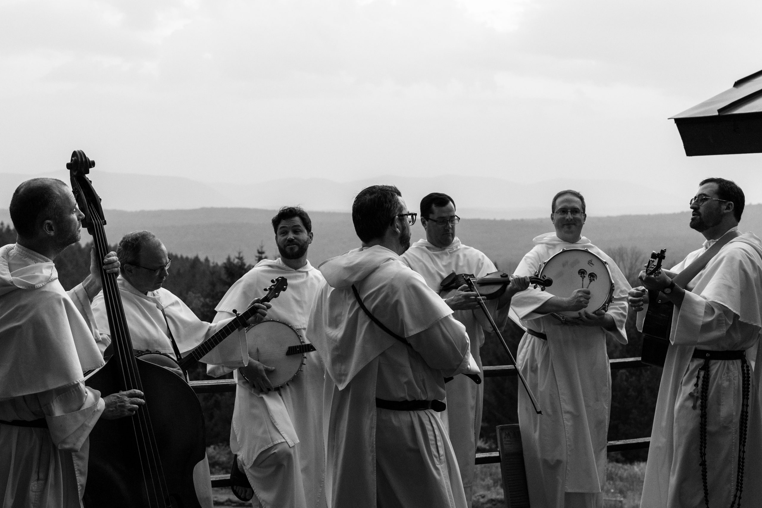 The Hillbilly Thomists hit the road with new album ‘Strange Land’ #Catholic Between ministering to their communities and traveling down the southern interstate from Macon, Georgia, to Birmingham, Alabama, the Dominican friars of The Hillbilly Thomists are balancing full-time religious life with the whirlwind of a regional tour.The music group’s latest project, “Strange Land,” was released as a surprise drop just a couple of days into their summer tour, offering listeners a blend of deep theological reflection and traditional Americana music.The surprise drop decision was driven largely by their demanding schedules. After writing and recording the tracks a year prior, the postproduction process had to fit around their primary duties as “hounds of the Lord.”“The postproduction process just takes a while because we are all full-time preachers and teachers and chaplains and pastors,” said Dominican Father Justin Bolger, who spoke with the National Catholic Register, the sister news partner of EWTN News, along with his band brothers while on the road.“After this kind of two-week stint that we do in the summer, the music takes a backseat to that … So it kind of came out when it came out.”Musically, “Strange Land” ranges from spiritual anthems like “In-A-My Soul” and “Gloria” to playfully titled tracks like “Garrigou” and “Good Old Elvis.”Dominican Father Thomas Joseph White, one of the founding members of the band who also serves as rector at the Angelicum in Rome, noted that the variety reflects the band’s distinct personalities while remaining grounded in shared themes.“There are some themes that show up, like pilgrimage and hope and struggle, that are in all the songs,” he explained. “It’s very consistent with what we’ve done on other albums, and it just comes out organically or naturally from our songwriting.”The record marks a step forward in technical execution for the ensemble. White described the album as representing a “slightly higher echelon of musical sophistication,” aided by tighter harmonies and complex arrangements. Unlike previous albums where the friars handled all engineering themselves in retreat houses, they hired a professional recording engineer for “Strange Land.” “It frees up more of the band to just focus on the music and to collaborate and just have that be the focus,” Bolger added.That spirit of collaboration is rooted deeply in their shared Dominican vocation. “We’ve known each other for years, and we’re all united in the Dominican order, so it just makes for a real atmosphere of ease,” said Dominican Father Jonah Teller, describing the mutual trust involved when bringing personal songs to the group.
The Hillbilly Thomists have released a new album called “Strange Land.” | Photo courtesy of the Hillbilly Thomists
As the band’s popularity grows, so does a devoted grassroots fan base. White observed a natural overlap between people interested in Catholic intellectual life — such as participants in the Thomistic Institute — and fans of their bluegrass music. That enthusiasm has even spilled over into unofficial merchandise crafted by fans. At recent shows, custom fan art has begun to emerge, including T-shirts designed by a college student featuring torch-bearing dogs alongside the caption “I’m a dog for my Lord,” as well as custom “Good Tree” hats.“You do see some kind of fan art emerge at these shows, which is charming,” Bolger noted. White deadpanned that the order was engaged in a “very serious lawsuit” to confiscate the student’s assets and protect its intellectual property, prompting laughter from the rest of the band.The group’s reach has extended all the way to the Vatican. Recalling a past meeting with Pope Leo XIV, White shared that while most gifts were set aside, the pontiff asked to keep The Hillbilly Thomists’ CDs close by. “So I don’t know if he listens to them, but I do know he made the point of keeping them,” White joked, adding: “It’s unclear at this point in time whether any of our lyrics will be quoted in forthcoming encyclicals, but there’s some speculation.”When asked about playing traditional American folk and bluegrass music, especially as the nation celebrates 250 years of independence, singer and mandolin player Dominican Father Austin Litke pointed out the unique place the band occupies within the genre.“The Christian part of American culture has not always been predominantly Catholic,” Litke noted.“To be able to take up that form of music and infuse it with Catholic doctrine, Catholic culture, and certainly Thomistic culture … we hope is part of the genius of the creativity that’s come out of our fraternal work.”The 11-show tour concludes on Saturday, Aug. 8, fittingly on the feast of St. Dominic, with a performance alongside the Dominican Sisters of St. Cecilia at the Dominican Campus in Nashville, Tennessee.As for how fans can support the new release, Bolger kept his message simple: “Let all the old people and the young people know that they can find it on Spotify.”This story was first published by the National Catholic Register, the sister partner of EWTN News, and has been adapted by EWTN News. The Hillbilly Thomists hit the road with new album ‘Strange Land’ #Catholic Between ministering to their communities and traveling down the southern interstate from Macon, Georgia, to Birmingham, Alabama, the Dominican friars of The Hillbilly Thomists are balancing full-time religious life with the whirlwind of a regional tour.The music group’s latest project, “Strange Land,” was released as a surprise drop just a couple of days into their summer tour, offering listeners a blend of deep theological reflection and traditional Americana music.The surprise drop decision was driven largely by their demanding schedules. After writing and recording the tracks a year prior, the postproduction process had to fit around their primary duties as “hounds of the Lord.”“The postproduction process just takes a while because we are all full-time preachers and teachers and chaplains and pastors,” said Dominican Father Justin Bolger, who spoke with the National Catholic Register, the sister news partner of EWTN News, along with his band brothers while on the road.“After this kind of two-week stint that we do in the summer, the music takes a backseat to that … So it kind of came out when it came out.”Musically, “Strange Land” ranges from spiritual anthems like “In-A-My Soul” and “Gloria” to playfully titled tracks like “Garrigou” and “Good Old Elvis.”Dominican Father Thomas Joseph White, one of the founding members of the band who also serves as rector at the Angelicum in Rome, noted that the variety reflects the band’s distinct personalities while remaining grounded in shared themes.“There are some themes that show up, like pilgrimage and hope and struggle, that are in all the songs,” he explained. “It’s very consistent with what we’ve done on other albums, and it just comes out organically or naturally from our songwriting.”The record marks a step forward in technical execution for the ensemble. White described the album as representing a “slightly higher echelon of musical sophistication,” aided by tighter harmonies and complex arrangements. Unlike previous albums where the friars handled all engineering themselves in retreat houses, they hired a professional recording engineer for “Strange Land.” “It frees up more of the band to just focus on the music and to collaborate and just have that be the focus,” Bolger added.That spirit of collaboration is rooted deeply in their shared Dominican vocation. “We’ve known each other for years, and we’re all united in the Dominican order, so it just makes for a real atmosphere of ease,” said Dominican Father Jonah Teller, describing the mutual trust involved when bringing personal songs to the group.
The Hillbilly Thomists have released a new album called “Strange Land.” | Photo courtesy of the Hillbilly Thomists
As the band’s popularity grows, so does a devoted grassroots fan base. White observed a natural overlap between people interested in Catholic intellectual life — such as participants in the Thomistic Institute — and fans of their bluegrass music. That enthusiasm has even spilled over into unofficial merchandise crafted by fans. At recent shows, custom fan art has begun to emerge, including T-shirts designed by a college student featuring torch-bearing dogs alongside the caption “I’m a dog for my Lord,” as well as custom “Good Tree” hats.“You do see some kind of fan art emerge at these shows, which is charming,” Bolger noted. White deadpanned that the order was engaged in a “very serious lawsuit” to confiscate the student’s assets and protect its intellectual property, prompting laughter from the rest of the band.The group’s reach has extended all the way to the Vatican. Recalling a past meeting with Pope Leo XIV, White shared that while most gifts were set aside, the pontiff asked to keep The Hillbilly Thomists’ CDs close by. “So I don’t know if he listens to them, but I do know he made the point of keeping them,” White joked, adding: “It’s unclear at this point in time whether any of our lyrics will be quoted in forthcoming encyclicals, but there’s some speculation.”When asked about playing traditional American folk and bluegrass music, especially as the nation celebrates 250 years of independence, singer and mandolin player Dominican Father Austin Litke pointed out the unique place the band occupies within the genre.“The Christian part of American culture has not always been predominantly Catholic,” Litke noted.“To be able to take up that form of music and infuse it with Catholic doctrine, Catholic culture, and certainly Thomistic culture … we hope is part of the genius of the creativity that’s come out of our fraternal work.”The 11-show tour concludes on Saturday, Aug. 8, fittingly on the feast of St. Dominic, with a performance alongside the Dominican Sisters of St. Cecilia at the Dominican Campus in Nashville, Tennessee.As for how fans can support the new release, Bolger kept his message simple: “Let all the old people and the young people know that they can find it on Spotify.”This story was first published by the National Catholic Register, the sister partner of EWTN News, and has been adapted by EWTN News.