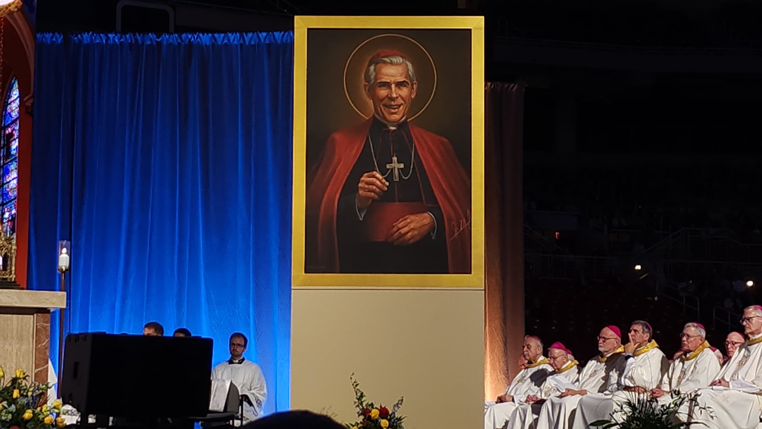 A ‘porter’ who led others to Christ: Archbishop Fulton Sheen declared ‘blessed’ – #Catholic – ST. LOUIS — Archbishop Fulton Sheen, despite his humble origins in small-town Illinois, aspired to great things as an academic and as a communicator of the Catholic faith. On Sept. 24, before a crowd of tens of thousands at The Dome at America’s Center, the farm-boy-turned-mass-media star was declared “blessed” after the reading of a decree signed by Pope Leo XIV, a fellow Midwesterner.Via his decree, Pope Leo announced Blessed Sheen’s feast day will be on Dec. 9, the anniversary of his death. His feast day is expected to be on the calendar of the Catholic Church in the United States.Cardinal Luis Tagle, the pope’s representative and the principal celebrant of the beatification Mass, reflected on the meaning of “blessed” during his homily — noting that throughout history many who shared the Christian faith suffered persecution, yet their lives were still marked by joy. It is Sheen’s deep, humble relationship with Jesus Christ and his radical solidarity with the poor and vulnerable that characterized his life as a missionary, one that all Catholics should emulate, Tagle said.Despite his massive worldly popularity and the fact that he personally accompanied countless converts in their journey to become Catholic, Tagle noted that Sheen did not “claim” the converts as his own but rather described himself as a mere “porter” who led people to the “open door of the house of God.”
 
 Cardinal Luis Tagle serves as the pope’s representative and the principal celebrant of the beatification Mass on Sept. 24, 2026, in St. Louis. | Credit: Jeffrey Bruno
 
 “It is for being a zealous and creative evangelizer, an advocate for mission that Fulton Sheen is called ‘blessed’ or ‘fortunate’ or ‘happy’… Blessed is the Evangelizer, converted by beholding and touching the wounds of the risen Christ in wounded brothers and sisters, blessed is the missionary who digs deep into the heart of the poor to meet Jesus there. Blessed Fulton J. Sheen!” Tagle proclaimed.Jam-packed crowds of Catholics of all ages — from the elderly who were around when Sheen’s shows first aired, to numerous families with small children — had descended on the stadium for the Mass, which began with a lengthy procession of some 1,000 priests, 89 bishops, and hundreds of seminarians and deacons.The actual moment when Sheen became “blessed” happened early in the proceedings, following the proclamation of a decree signed by Pope Leo XIV. As is customary at beatifications, the decree was read first in Latin by Tagle, the pope’s representative and the pro-prefect of the Dicastery for Evangelization, and afterward in the vernacular — in this case English — by Bishop Louis Tylka of Peoria, Illinois, in whose diocese Sheen was born.Immediately following the reading, a portrait of Blessed Sheen was revealed showing him with a halo, to thunderous applause. The same portrait was simultaneously unveiled at his tomb at the Cathedral St. Mary of the Immaculate Conception in Peoria.
 
 A new image of Blessed Fulton Sheen is displayed after he is declared “blessed” at the Mass for his beatification on Sept. 24, 2026, at The Dome at America’s Center in St. Louis. | Credit: Jeffrey Bruno
 
 Earlier in the day, Monsignor Jason Gray, executive director of the Archbishop Fulton J. Sheen Foundation, announced that six purported miracles are attributed to the intercession of Sheen as part of the process that could lead to his canonization. Any purported miracle attributed to Sheen’s intercession that has taken place since Pope Francis announced his beatification in July 2019 can count toward his eventual canonization, which typically requires a second miracle to move forward.James Fulton Engstrom, recipient of the confirmed miracle that cleared the way for Sheen’s beatification, survived in spite of having spent 61 minutes without a heartbeat. The healthy 16-year-old presented several of Sheen’s relics during the beatification Mass today.Catholics from all over the world hailed Sheen’s example as a highly creative and effective missionary, who used every means available to him to share the love of Christ.Father Solomon Patrick Zaku, national director of the Pontifical Mission Societies in Nigeria, flew to the U.S. for his first-ever visit to the country to attend the beatification of Sheen, who previously served as the Pontifical Mission Societies’ national director for the U.S.“While I was in the seminary, I read about his book and about his life, and I was somewhat touched by his life. One of the things I have learned from him is the Holy Hour, spending an hour daily, and that has been part of my daily routine, which has been my source of inspiration,” Zaku said. “As the national director of the Pontifical Mission Societies in Nigeria, [we] promote the Mission Rosary, which Archbishop Fulton Sheen introduced … I pray it daily.”