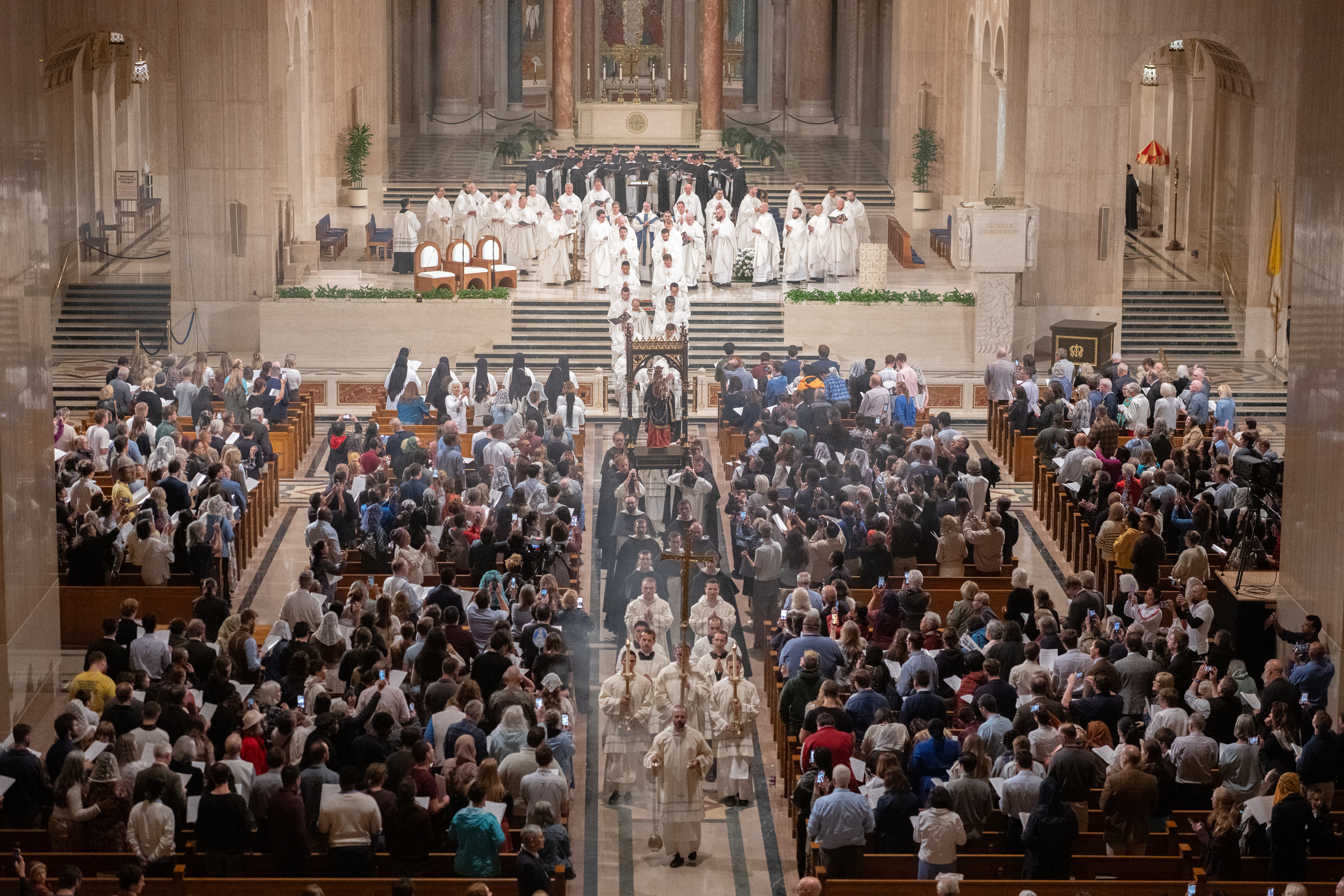 About 3,000 people gather in Washington, DC, for rosary pilgrimage – #Catholic – WASHINGTON — Thousands of Catholics who gathered at the Basilica of the National Shrine of the Immaculate Conception on Saturday got a head start on the approaching month of the rosary by participating in a daylong event featuring prayer and talks centered on the power of the Marian prayer.The fourth annual Dominican Rosary Pilgrimage drew an estimated 3,000 people, with tens of thousands of others joining via livestream broadcast.Hosted by the Dominican Friars of the Province of St. Joseph, the event included opportunities for joining in Eucharistic adoration and receiving the sacrament of reconciliation.“Every year the pilgrimage grows. Every year, more people join us and every year those prayers are lifted up to heaven with greater enthusiasm,” said Dominican Father Patrick Briscoe, promoter general for social communication of the Province of St. Joseph, which extends from New England to Virginia to Ohio.
 
 Pilgrims sit shoulder to shoulder in the basilica, some with hands clasped in prayer, during the Vigil Mass at the Basilica of the National Shrine of the Immaculate Conception in Washington, D.C., for the Dominican Rosary Pilgrimage on Saturday, Sept. 26, 2026. | Credit: Jeffrey Bruno
 
 “It’s such a beautiful event,” said pilgrim Lauren Rodriguez, who traveled from Miami. “This is the second time I’ve come and this year I brought my husband. I just thought it was so impactful to see so much beauty, prayer, and truth in the preaching. It’s incredibly peaceful for as many activities that there are throughout the day.”In preparation for the event, an estimated 100,000 Catholics participated in a nine-month novena, beginning on Jan. 31 and ending on Sept. 26, according to Dominican Father John Paul Kern, the St. Joseph province’s executive director.
 
 Dominican friars carry a statue of Mary holding the infant Jesus through the basilica during the rosary procession at the Basilica of the National Shrine of the Immaculate Conception in Washington, D.C., for the Dominican Rosary Pilgrimage on Saturday, Sept. 26, 2026. | Credit: Jeffrey Bruno
 
 “I think Our Lady brings us closer to him and reveals something to us about her son in a very special way with him here at this event,” Kern said.Dominican Father Peter John Cameron, the event’s principal speaker, described the rosary as a gift and a “chain that unites people to God.”
 
 A man bows his head over clasped hands while seated in the church at the Basilica of the National Shrine of the Immaculate Conception in Washington, D.C., for the Dominican Rosary Pilgrimage on Saturday, Sept. 26, 2026. | Credit: Jeffrey Bruno
 
 “The rosary is something truly unique and indescribably precious,” he told EWTN News. “Because more than just a form of prayer, the rosary is a relationship. The rosary is a dynamic experience of our sonship, of our daughtership, in God.”“For someone like me who’s so busy, and so many people are busy, it’s a day dedicated to prayer, to soak it in, receive the graces,” Rodriguez told EWTN News. “You meet so many wonderful people from all over. It really is reaching so many people and touching so many hearts.”The Catholic Church dedicates the entire month of October to the most holy rosary and celebrates the feast of Our Lady of the Rosary on Oct. 7.
 
 Children sit with adults beside a stroller in a crowded pew at the Basilica of the National Shrine of the Immaculate Conception in Washington, D.C., for the Dominican Rosary Pilgrimage on Saturday, Sept. 26, 2026. | Credit: Jeffrey Bruno